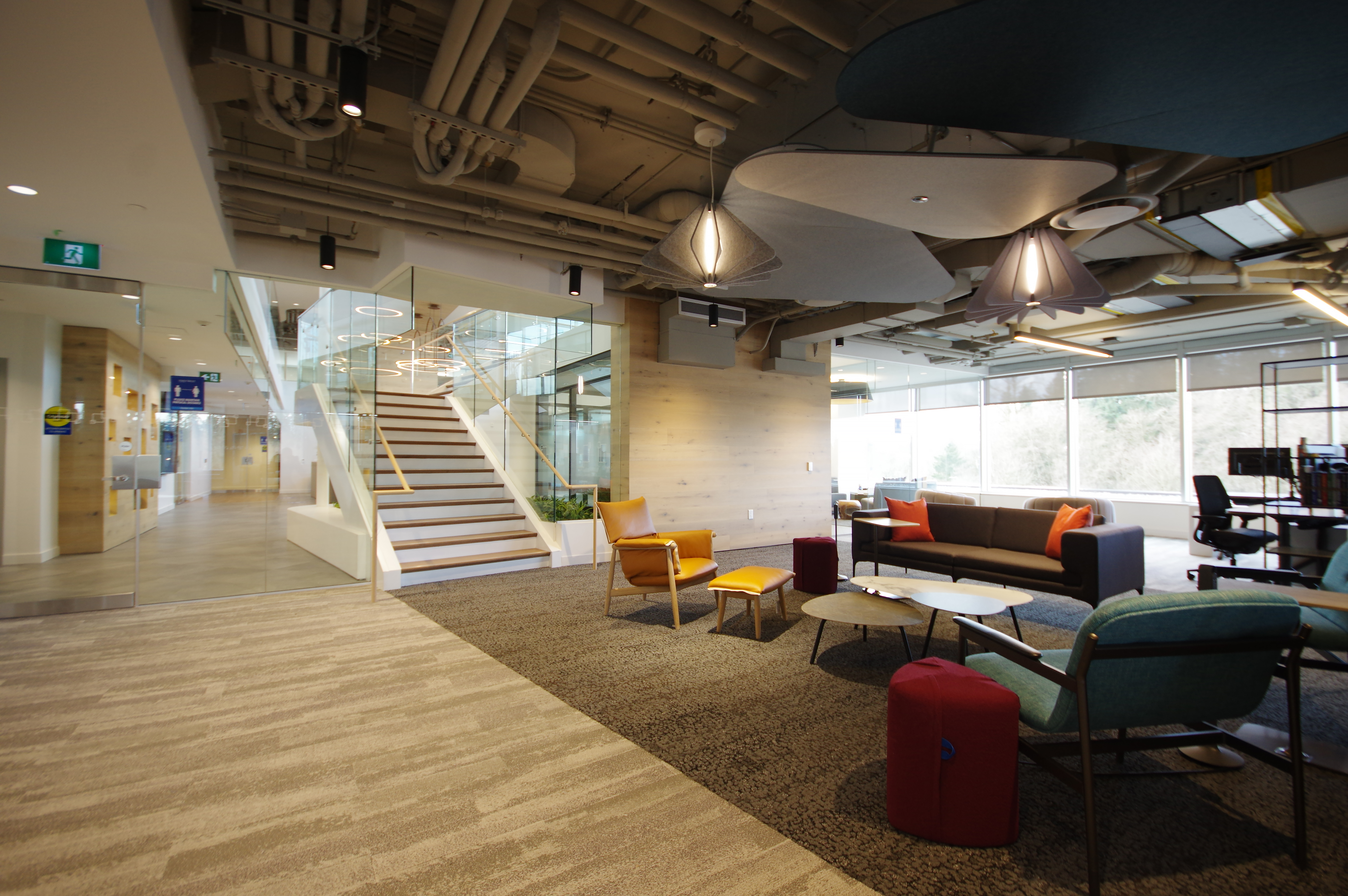 A perspective view of a First West Credit Union typical floor with furniture, desks, lighting and a staircase to the next level.